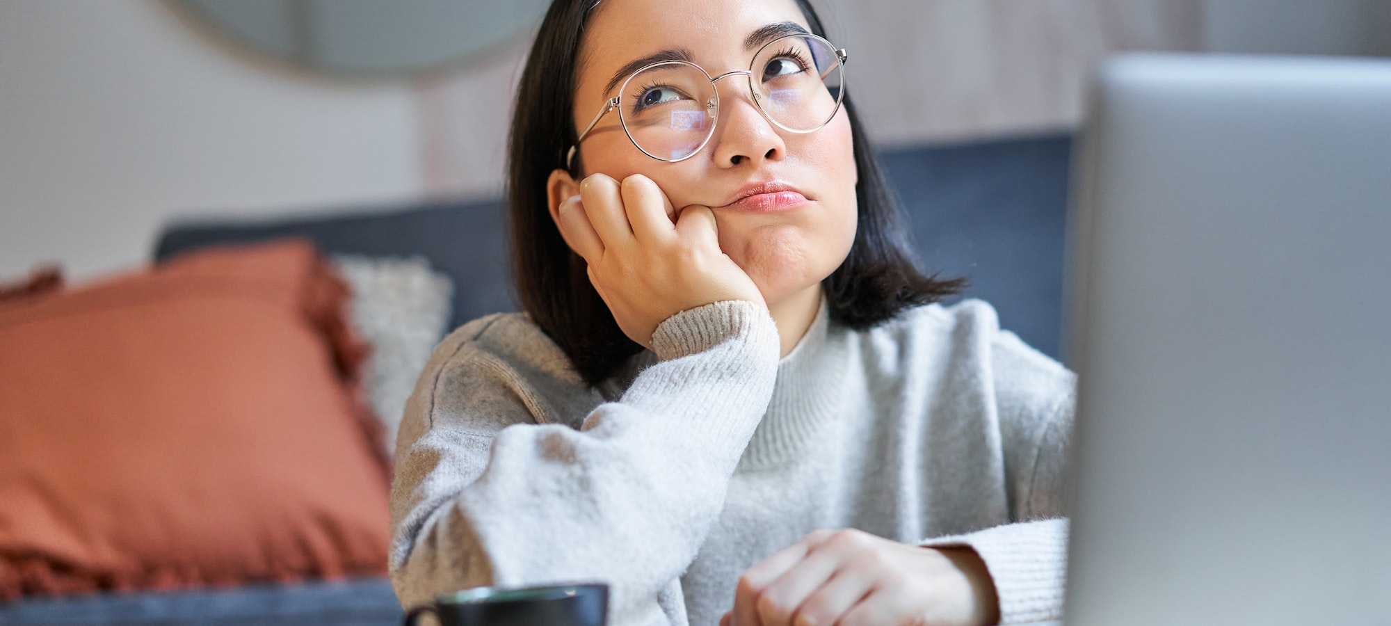 korean young woman staring blankly at ceiling bored near laptop