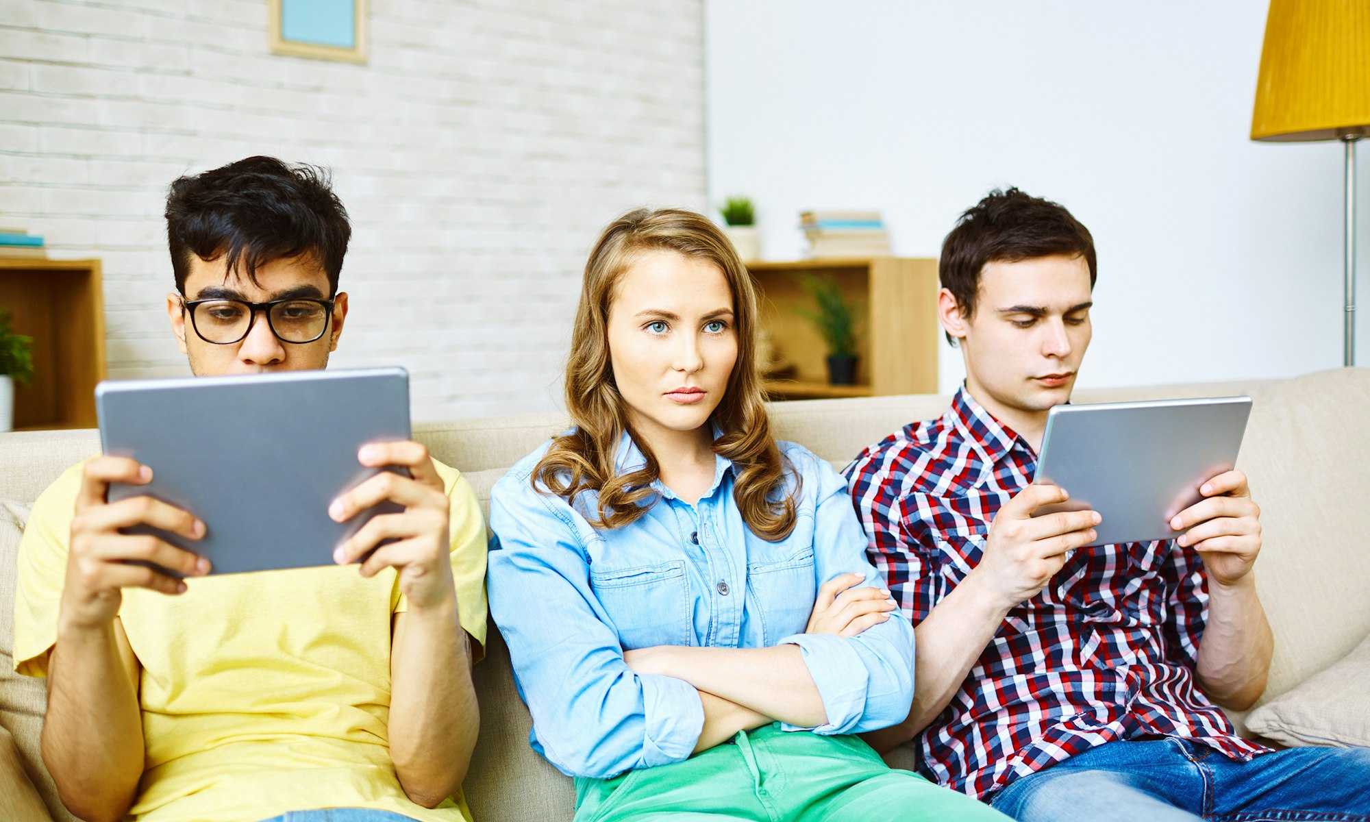 Woman cross-armed and angry next to two males staring at tablets