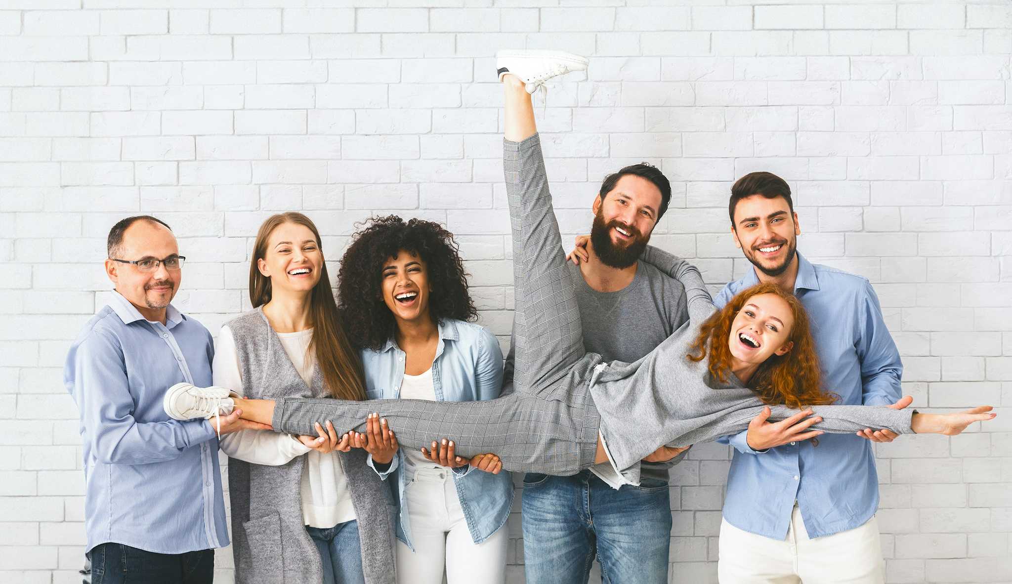 Culture at work - women and men holding another woman in the air