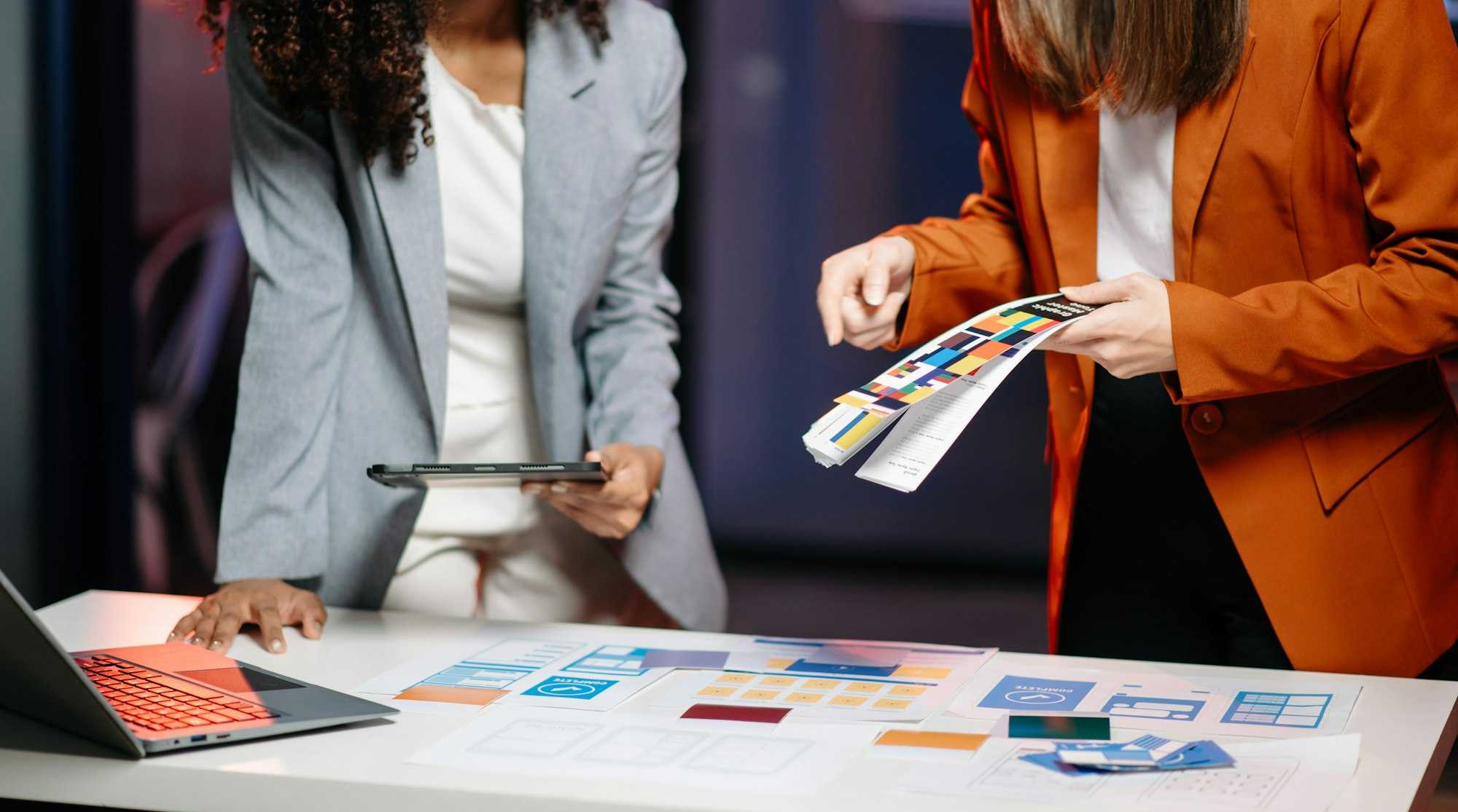 Two women choosing colours from swatches for new website design