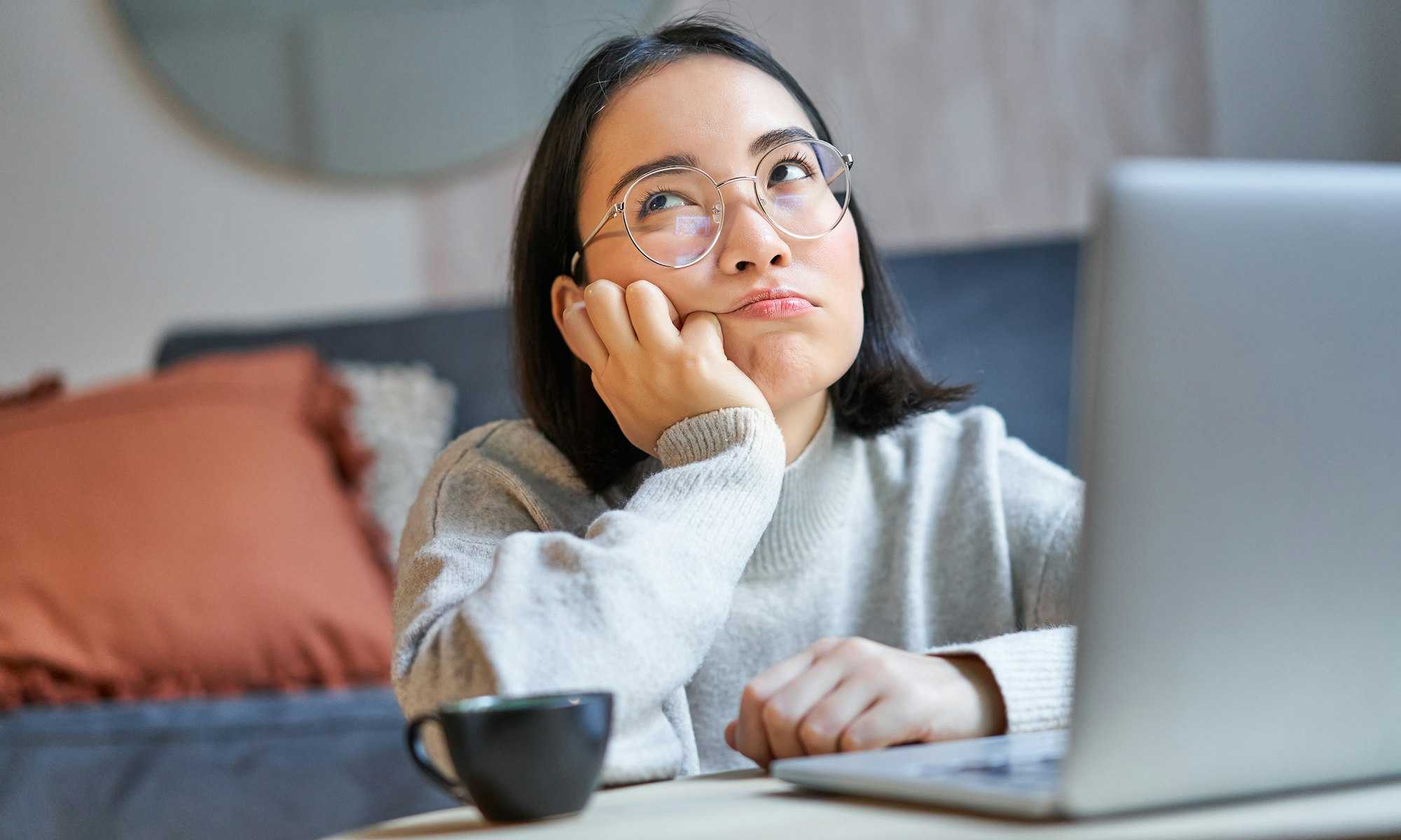 korean young woman staring blankly at ceiling bored near laptop