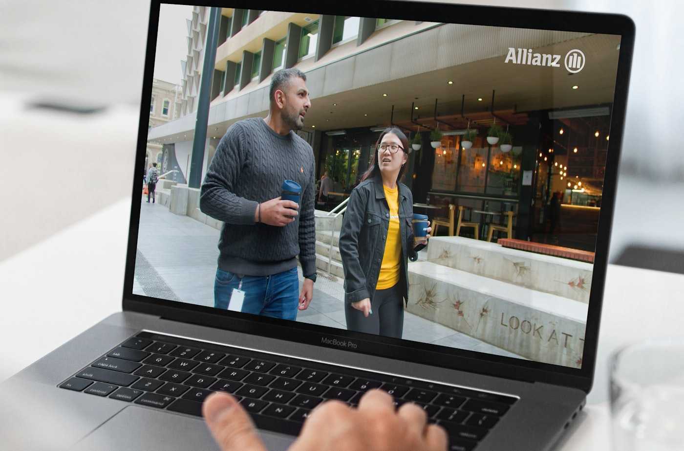 Two colleagues walking and talking with coffee cups | Belong Creative