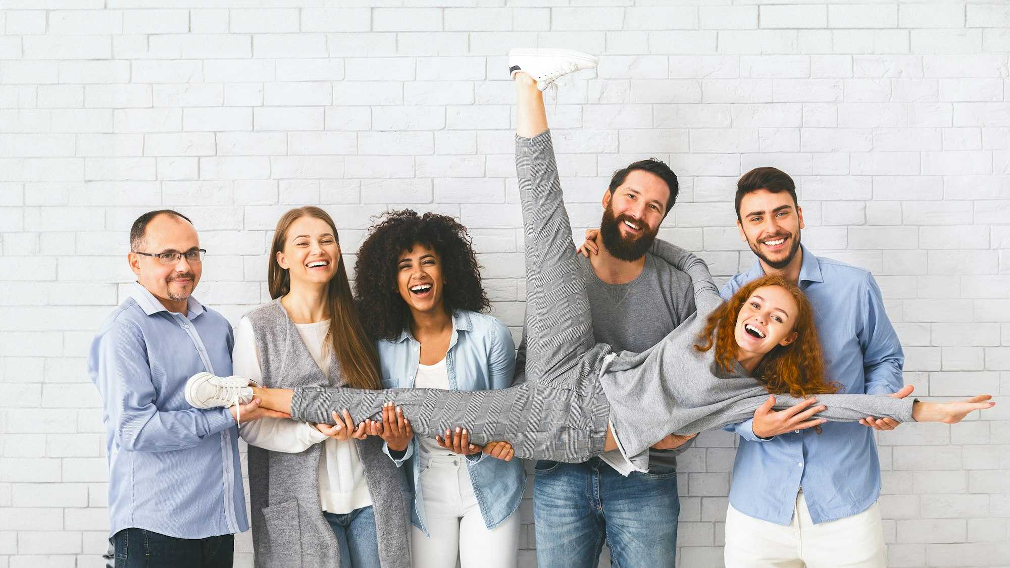 Culture at work - women and men holding another woman in the air