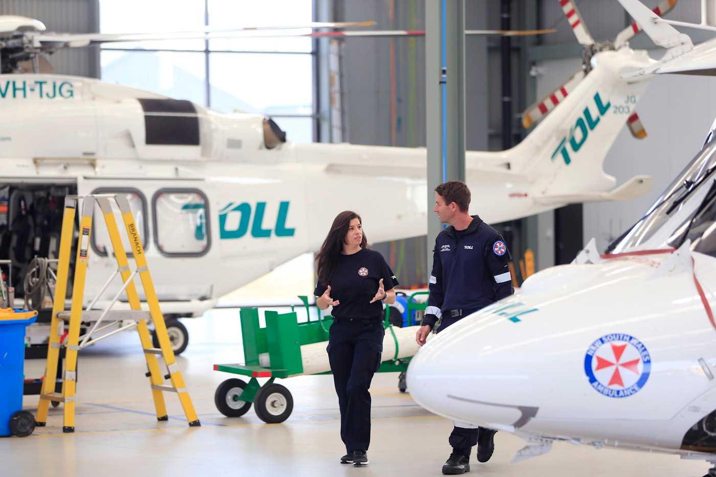 Two employees discussing beside Toll helicopters | Belong Creative