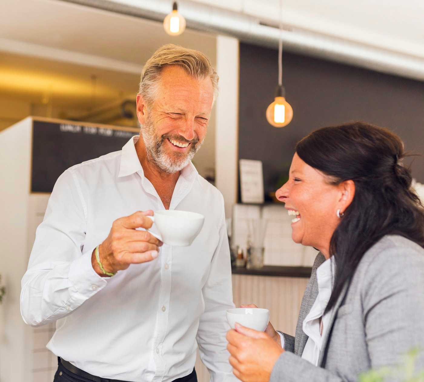 Two colleagues sharing a laugh over coffee | Belong Creative