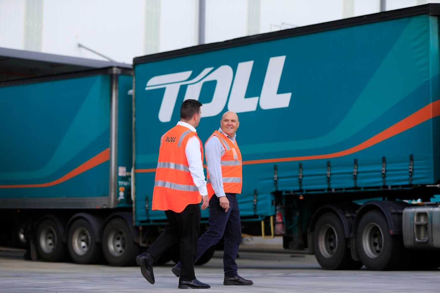  Employees in safety vests walking beside company trucks | Belong Creative