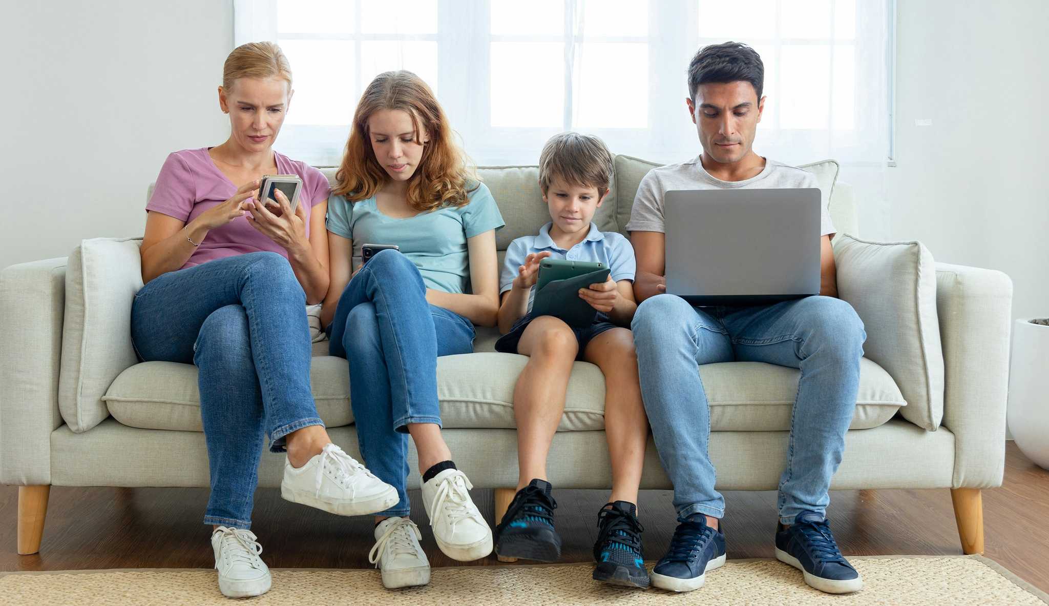 family all using screens next to each other on couch