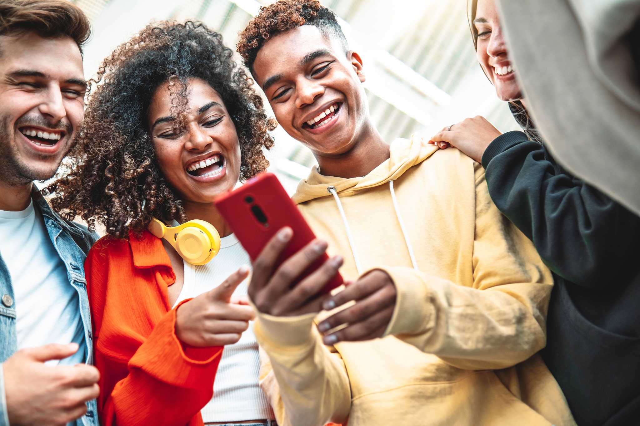 Young people crowded around a mobile phone.
