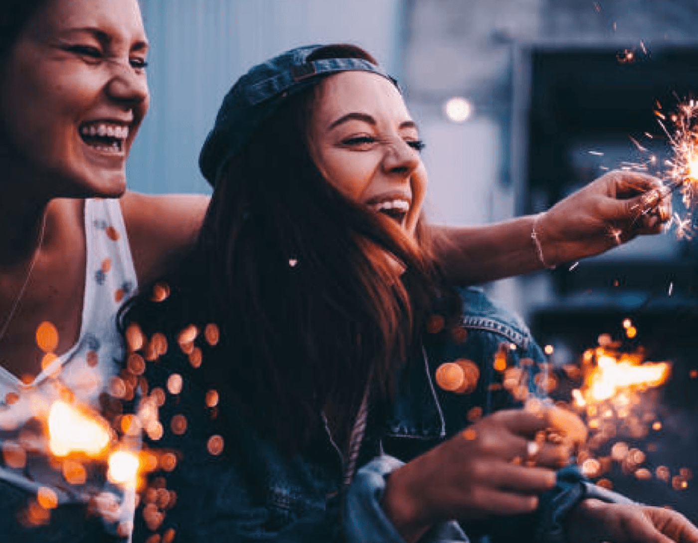 Two young woman laughing as they hold sparklers